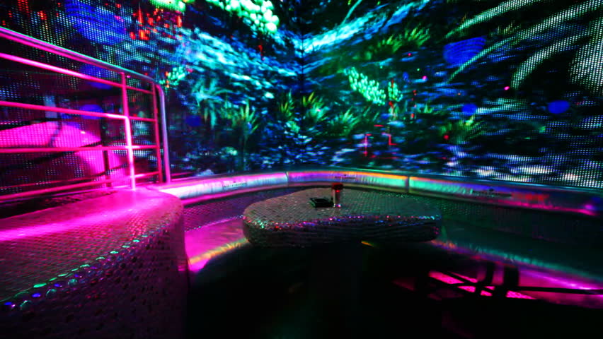 table and sofa in nightclub with bright LED illumination on walls