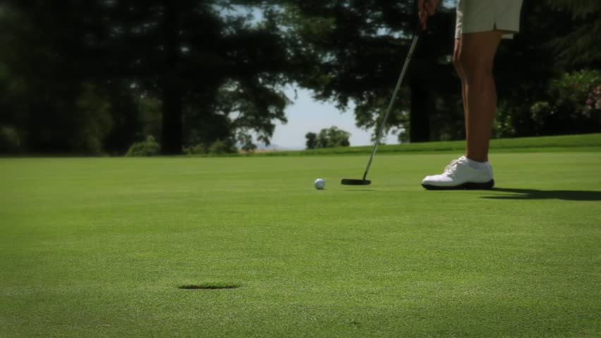 Woman on putting green hits ball in hole and cheers