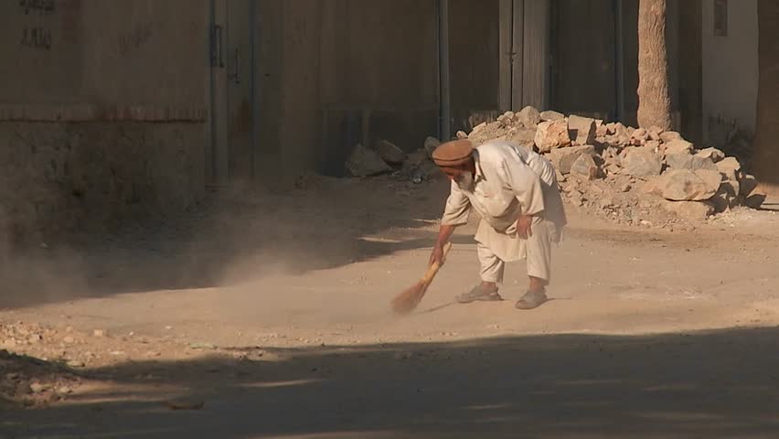 KABUL, AFGHANISTAN - CIRCA 2009: An old man sweeps the street and clears stones and rocks circa 2009 in Kabul, Afghanistan. Afghanistan is an impoverished and least developed country, one of the world's poorest.