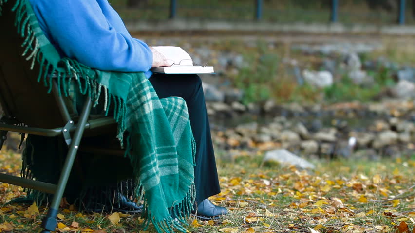 Senior woman enjoying  Retirement with a book at autumn park by the river Unrecognizable Person,  Side View