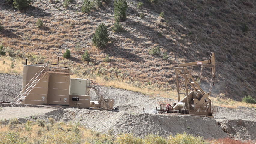 Oil well pumping crude from deep desert valley between mountains in central Utah. Propane motor powers the pump that extracts the oil.