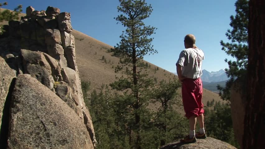 JOSHUA TREE, CA - CIRCA 2009: A man steps up onto a boulder and looks into the distance circa 2009 in Joshua Tree.