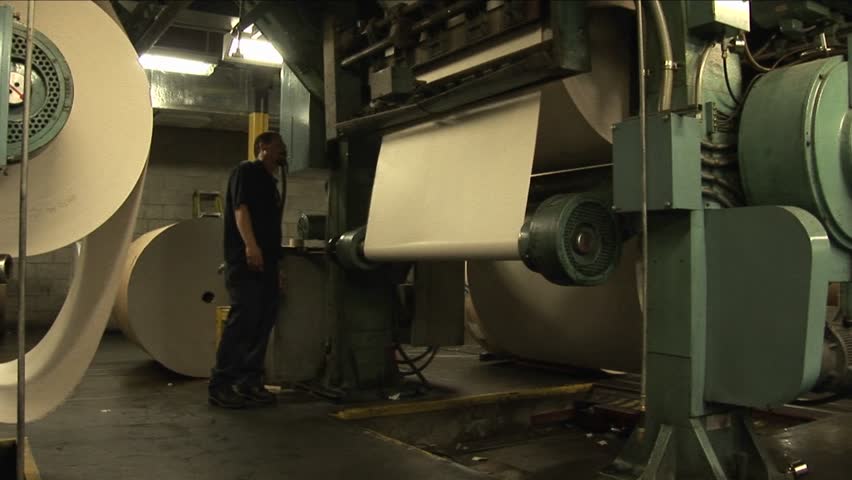 Workers load paper rollers in newspaper factory.