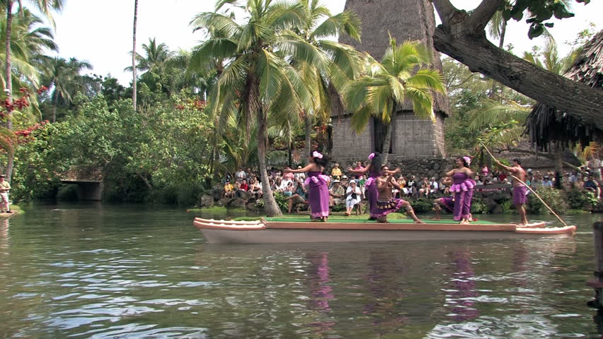 Polynesian Cultural Center in Laie Oahu Hawaii. Canoe show with dancers from Hawaii. Tourists on the main lagoon. Purple skirts on beautiful dancers. Water, lagoon and palm trees.