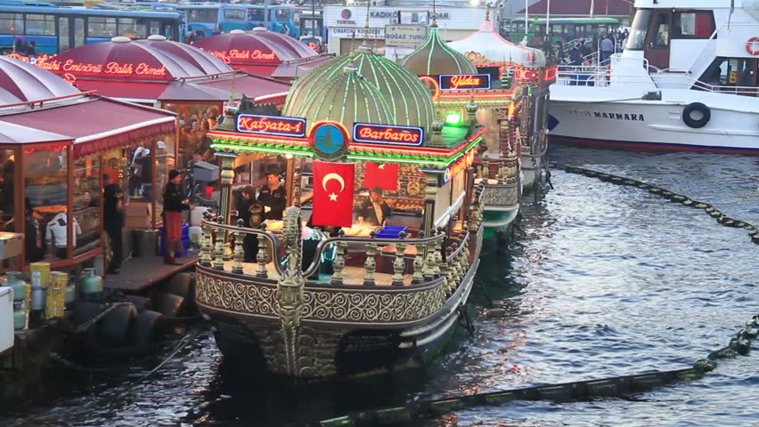 ISTANBUL - DECEMBER 23: Street vendors begins to cook and sell fish food on colorful boats at Golden Horn coast on December 23, 2010 in Istanbul, Turkey. Fast food very common at Eminonu region.