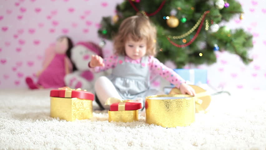 Baby girl is preparing a Christmas gifts and looking at camera 