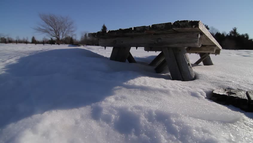 Wooden picnic table half-buried in snow
