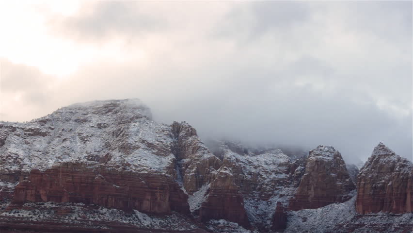 Clouds move slowly over the mountains of Sedona, Arizona after a light dusting of snow in the morning.