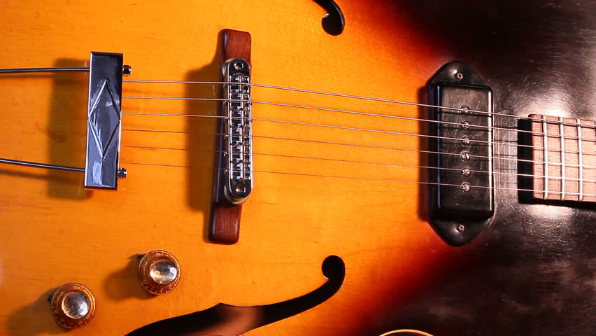 A closeup of a  musician playing a tune on a electric retro rock guitar.