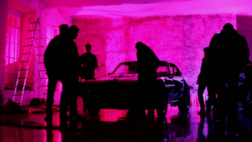 People consider mustang car standing in dark, violet studio 