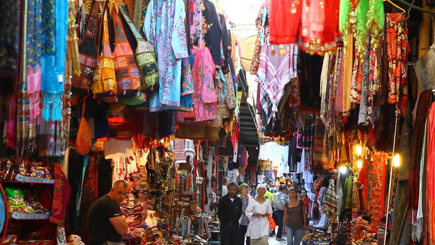 JERUSALEM, ISRAEL - CIRCA OCT 2011: Tourists look for souvenirs in a colorful alley of a bazaar market circa October 2011 in Jerusalem.