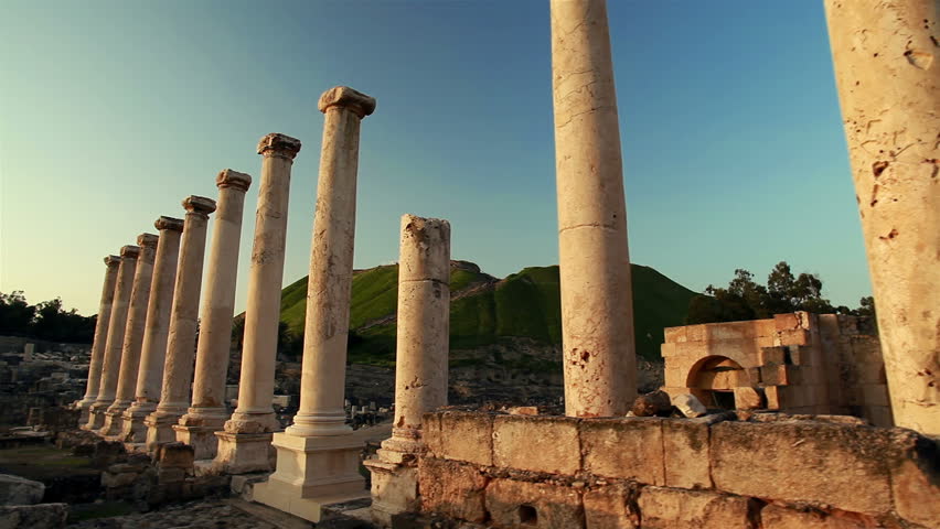 Dolly move using the slider, right to left of columns left standing at the Beit Shean ruins in Israel,  A green hill can be seen in the far background.