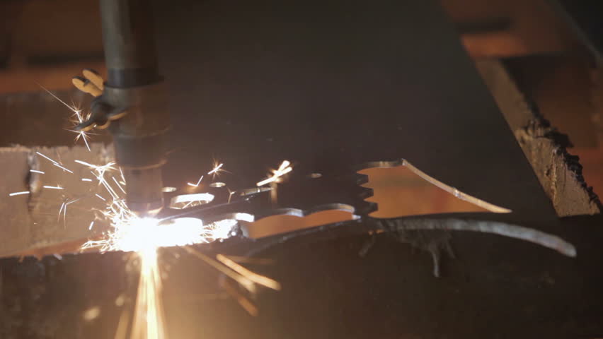Plasma cutter slicing through hard steel plate fast. Cutting a decoration or part used in industry. Sparks and molten metal from automatic machine. Industrial equipment. 