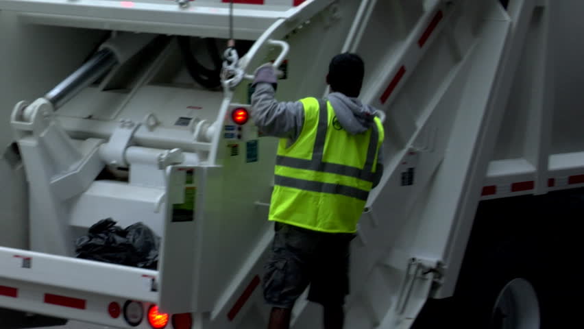 BOSTON, MA - CIRCA 2009: Garbage truck drives away with sanitation worker on back circa 2009 in Boston.