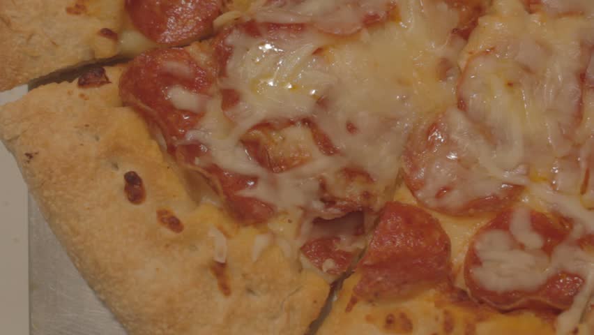 Slice of pepperoni pizza is pulled from a pie, then another