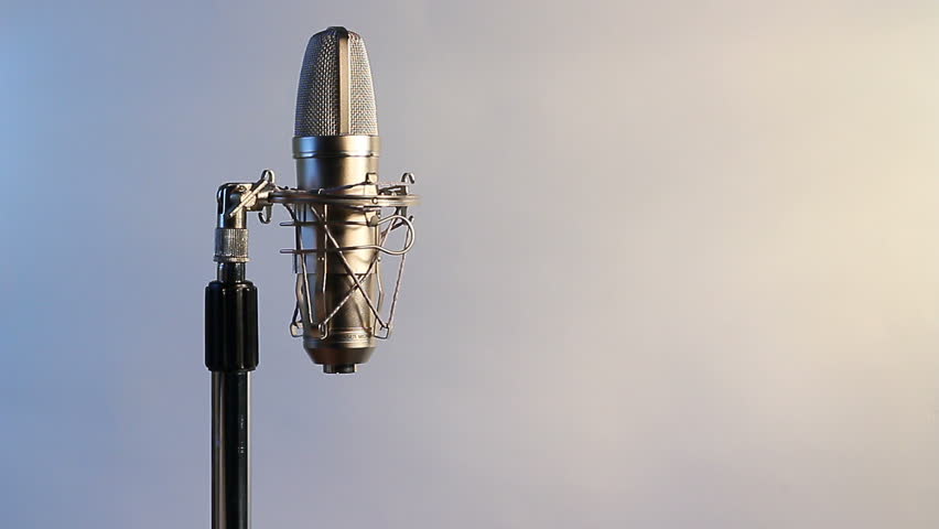 A closeup view of vocal condenser mic with man attaching mic cord.White background for text.