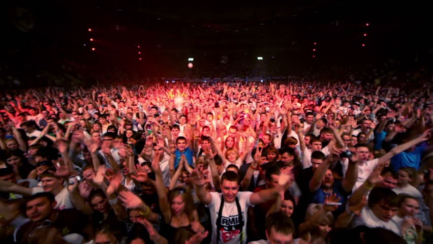 MOSCOW - MAY 6: People stand hands up at rave party in large hall with red illumination during Armin Only show on May 6, 2011 in Moscow, Russia.