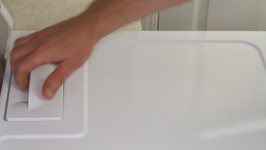 Male hand pulling out and cleaning the clothes dryer lint trap dirt collector of excess dust and fibers.