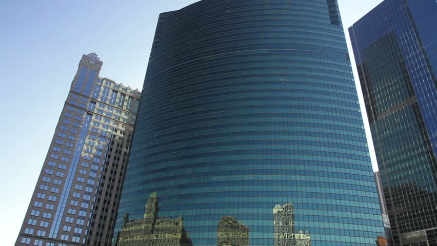 Smooth, low angle tracking shot, taken from a boat, as it rides down the Chicago River and spins around a corner with skyscrapers, and under an elevated train bridge as the train goes by.