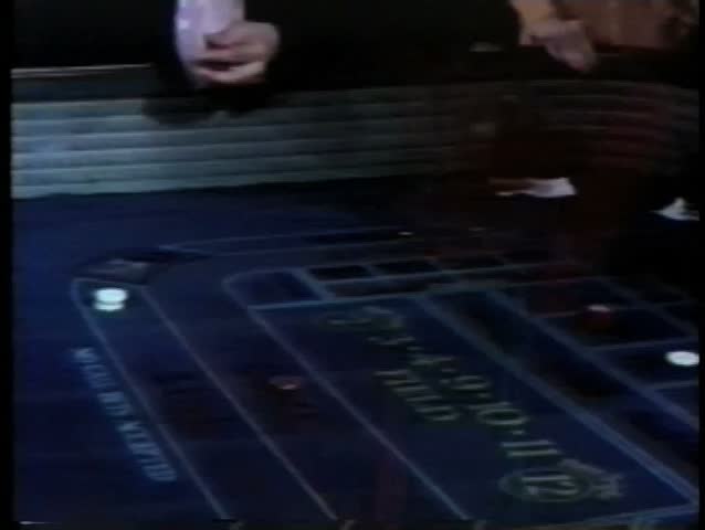 Man tossing dice on craps table in casino
