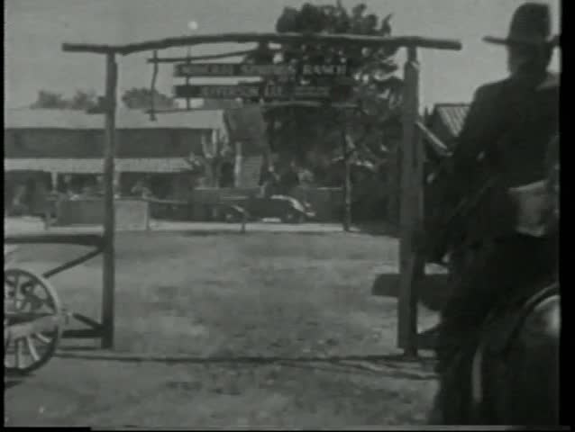 Rear view of cowboys on horseback riding into ranch