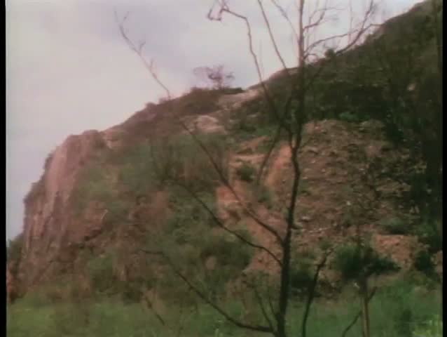 Wide shot men holding spears standing on a cliff