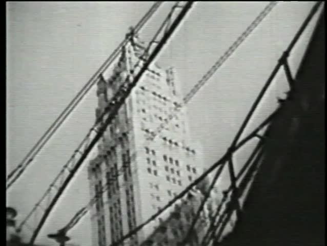 Low angle view of skyscraper behind elevated subway, 1930s