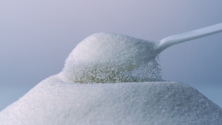 White spoon scoops up sugar