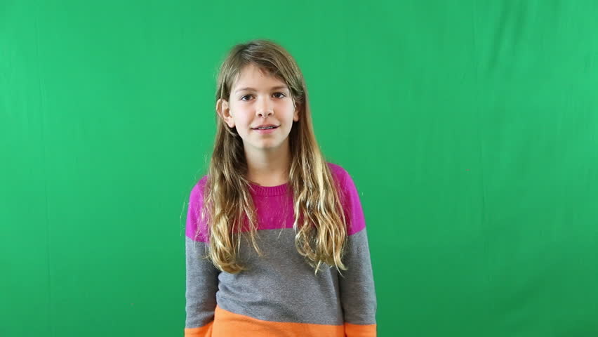 A Preteen Girl Looking At The Camera And Smiling In Front Of A Green