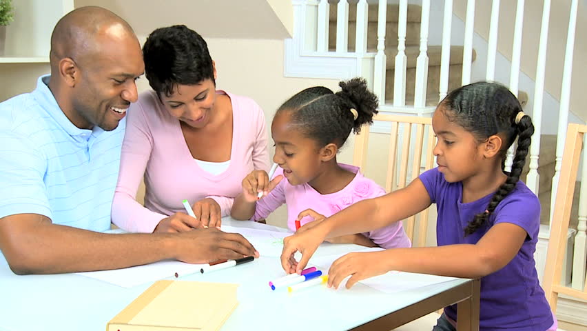 Young african american parents watching their cute young daughters using coloring crayons