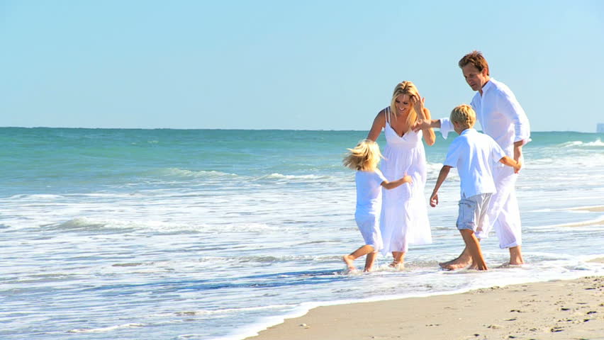 Attractive caucasian parents with their children on their back on the beach