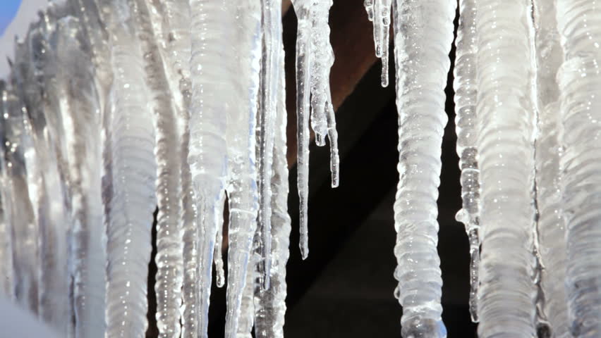 Icicles hanging from roof begin to melt with the coming of spring. Closeup.