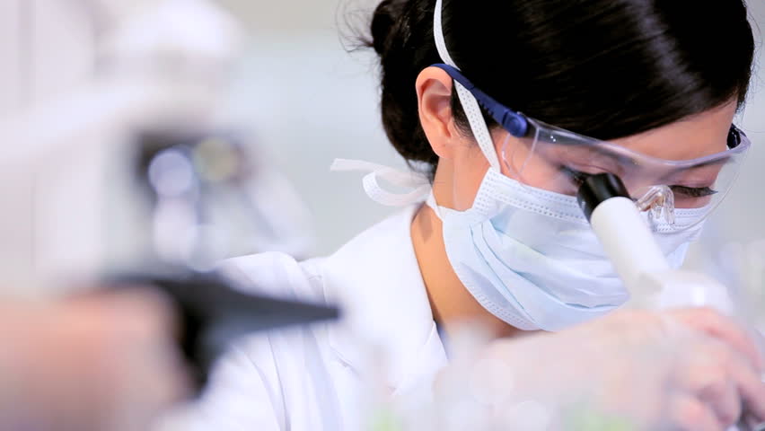 Asian chinese lab assistant examining medical specimens under a microscope
