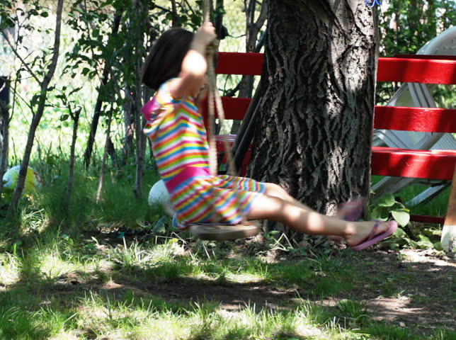 Young girl spinning in a tree swing and smiling