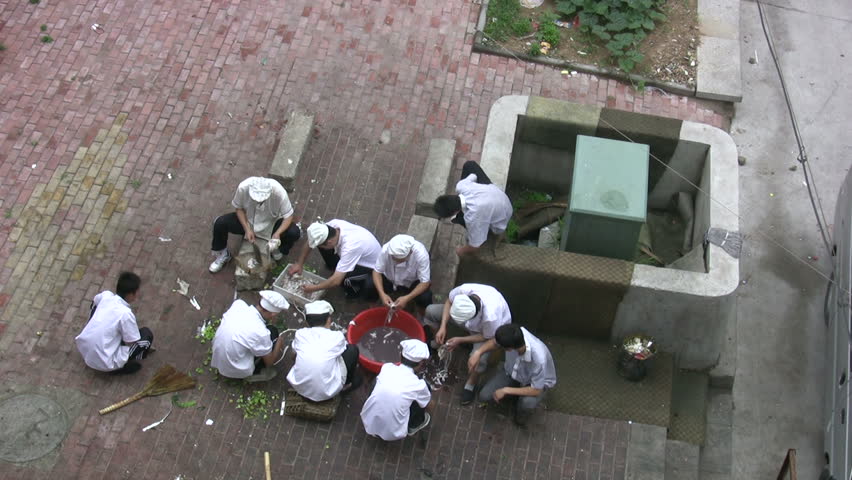 Chinese cooks are preparing for a work day at the back of a restaurant in Qingdao