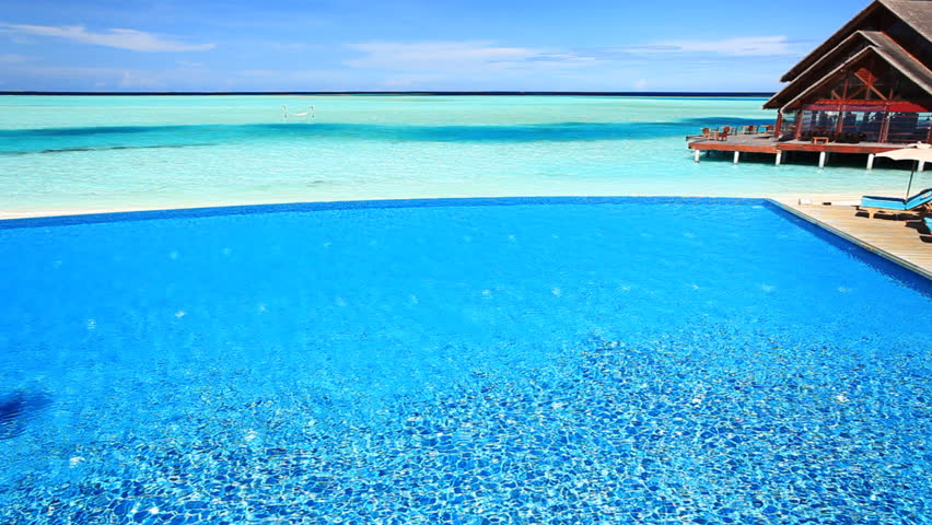 Young woman swimming across infinity pool in tropics
