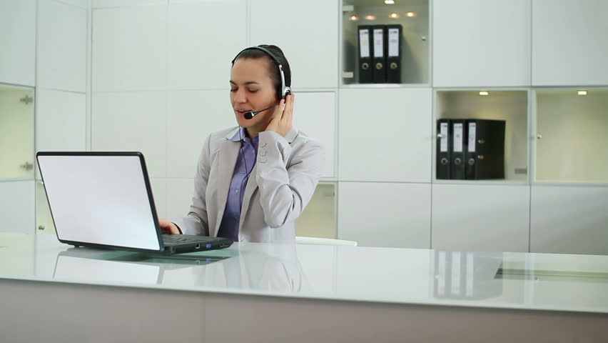 Helpdesk consultant talking on headset in front of the laptop
