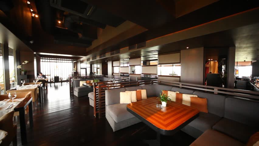 Man sits in restaurant lounge at little table near to big sofas and tables