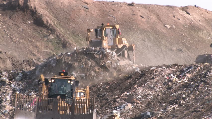 Garbage dump in Utah. Bull dozers moving garbage and trash around. A mountain of a landfill. Pollution and debris from business and residence household waste. Environmental waste non biodegradable.