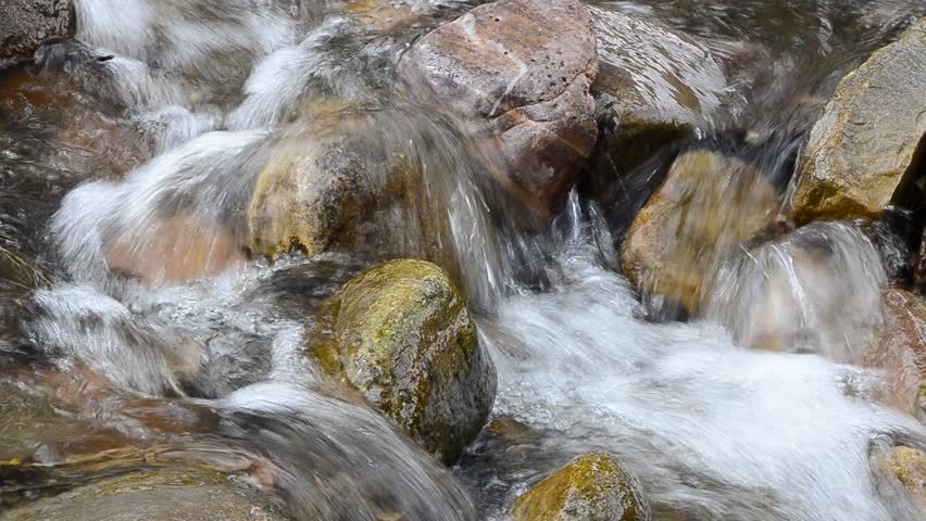 Mountain stream or creek flowing past mossy rocks