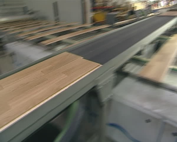 parquet production workshop. two crossing escalators and floorboards moving on them. workers in distance.
