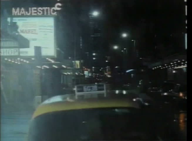 Taxi driving through New York City street on rainy night