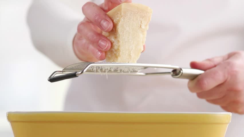 Lasagne being sprinkled with freshly grated Parmesan cheese