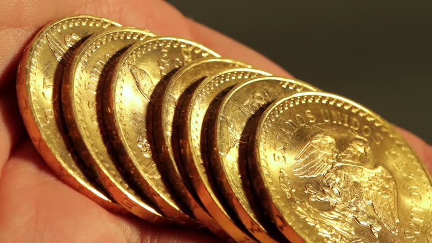 Gold Coins On Hand (HD). Pure gold bullion coins. These are called Centenario 50 gold peso coins 1945 vintage. Ambient audio included. 