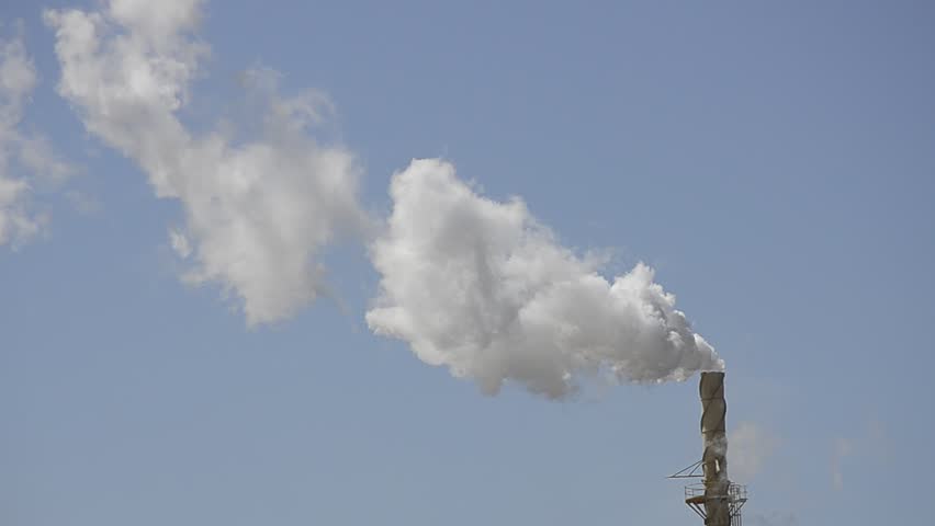 Factor smoke stack on blue sky day releasing smoke and pollution into the air