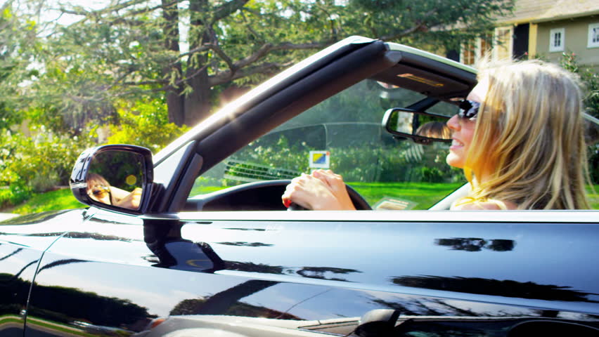 Young girls in a convertible cruising past luxury homes in California