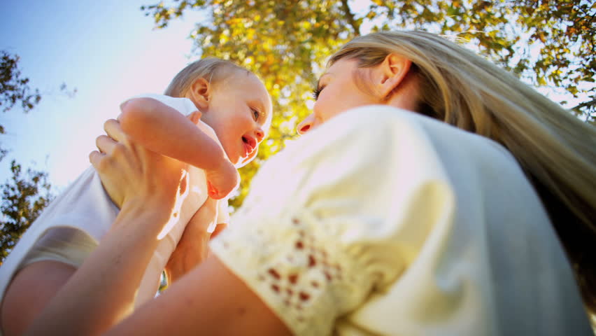 Beautiful young mother and baby laughing together as she is swung up in her mothers arms