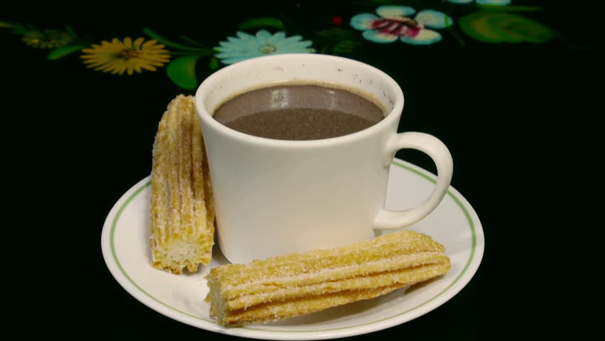 Churros with Hot Cocoa (HD). Sweet fried churros with hot cocoa cup being dipped and eaten. Spanish and Mexican delicacy for dessert. 