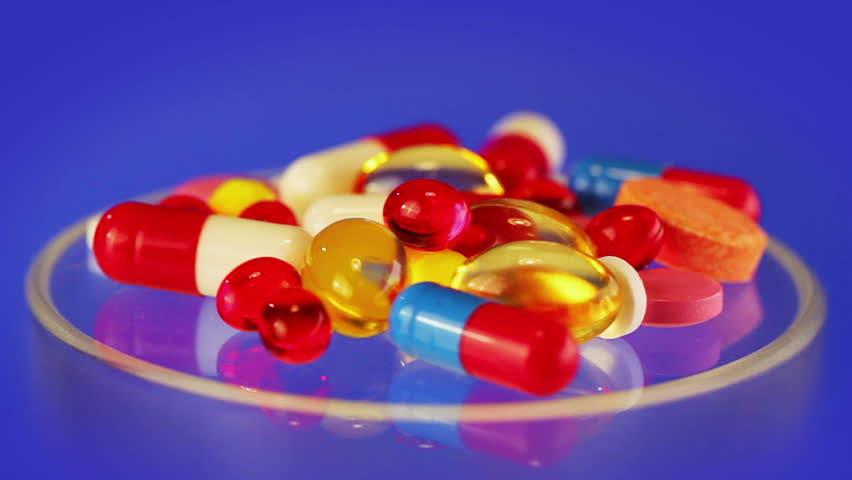 Pills and tablets heap rotating on blue medical concept, loop ready