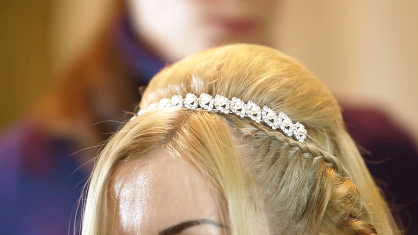 Hairdresser pinning up bride's hairstyle before the wedding